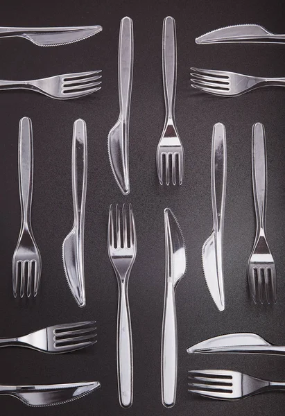 Plastic cutlery scattered over red background