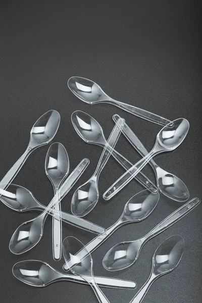 Plastic spoons scattered over black background