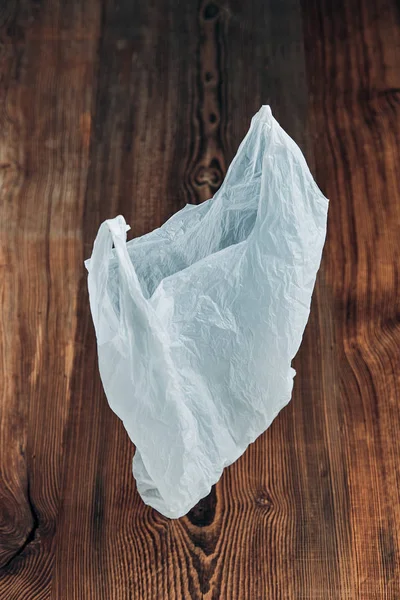 Weiße leere Plastiktüte schwebt über hölzernem Hintergrund — Stockfoto