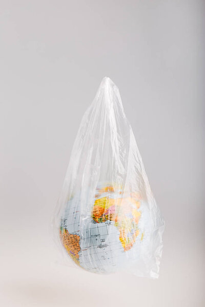 Глобус в пластиковом пакете. Земля загрязнена пластиковыми отходами

