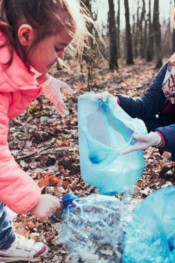 Aile bir ormanı temizliyor. Gönüllüler poşetlere plastik atık topluyor. Plastik kirliliği ve çok fazla plastik atığı kavramı. Çevresel bir sorun. Çevresel hasar. Çevreye karşı sorumluluk. Gerçek insanlar, otantik durumlar.