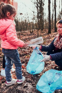Aile bir ormanı temizliyor. Gönüllüler poşetlere plastik atık topluyor. Plastik kirliliği ve çok fazla plastik atığı kavramı. Çevresel bir sorun. Çevresel hasar. Çevreye karşı sorumluluk. Gerçek insanlar, otantik durumlar.