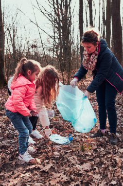 Aile bir ormanı temizliyor. Gönüllüler poşetlere plastik atık topluyor. Plastik kirliliği ve çok fazla plastik atığı kavramı. Çevresel bir sorun. Çevresel hasar. Çevreye karşı sorumluluk. Gerçek insanlar, otantik durumlar.