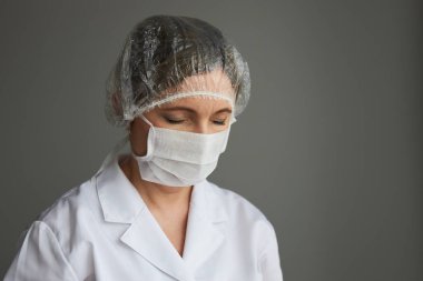 Yüzü maskeyle kaplı bir doktor. Virüs bulaşmasını önlemek ve hastalığın yayılmasını önlemek için üniforma ve maske takan genç bir kadının portresi. Gerçek insanlar, otantik durumlar.