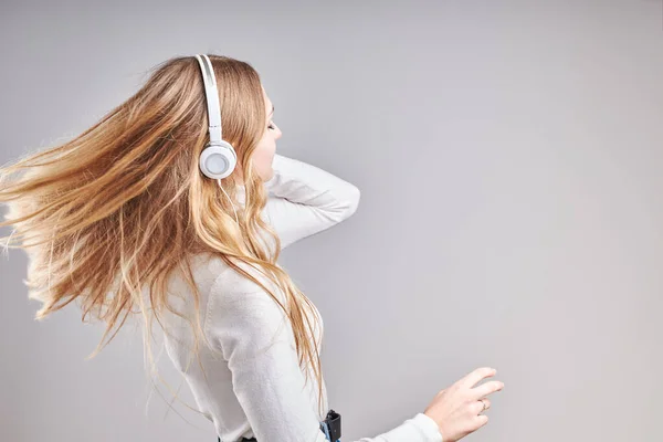 年轻女子在观看音乐流媒体内容时 喜欢看视频 喜欢和朋友们用智能手机耳机在灰蒙蒙的背景下做手势聊天 — 图库照片