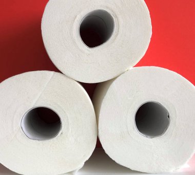 Kırmızı arka planda üç rulo beyaz tuvalet kağıdı, hijyen, makro fotoğraf.