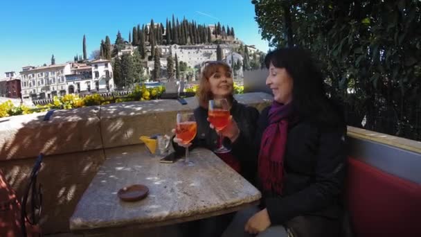 Two girls drink the Spritz cocktail in the background of Castel San Pietro — Stock Video