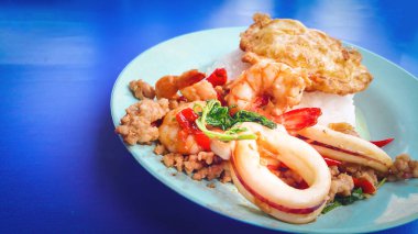 Pirinç tepesinde tavada kızartılmış domuz eti ve deniz ürünleri, fesleğen ve kızarmış yumurta, Fesleğenli kızarmış pilav ile