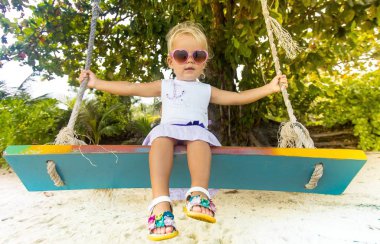 Mutlu çocuk salıncak üzerinde zevk özgürlük ve yaz deniz kıyısında.