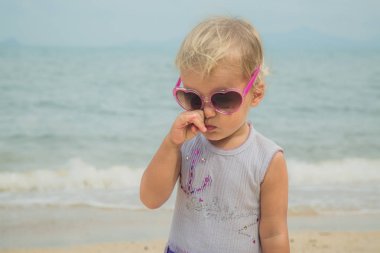 Kıyıda duran güneş gözlüklü çocuk.