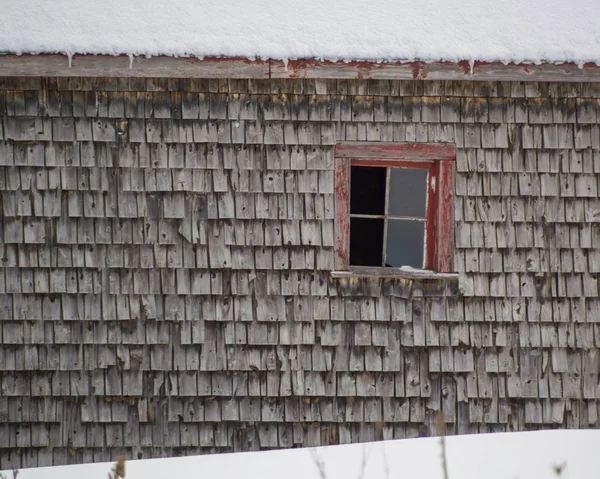 Alte verwitterte Zeder schüttelt Schindeln Scheune mit rotem Fenster Winter — Stockfoto