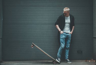 Genç adam patenci ile uzun tahta duruyor 