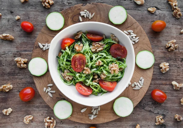 Rå courgette pasta med tomater og valnød med pesto i hvid skål. Udsigt fra oven - Stock-foto