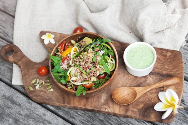 Salat med quinoa, zucchini og arugula i træskål på træpladen - Stock-foto