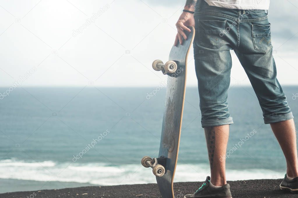 Back view of a skater standing on a high mountain 