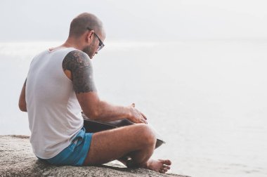 Adam taşa oturmuş ve hangdrum oynamak