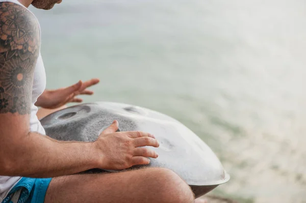 Primer plano de manos masculinas pagando tambor colgante en la playa — Foto de Stock