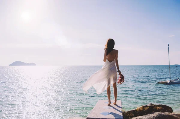 Bella sposa si trova su una scogliera sopra il mare — Foto Stock