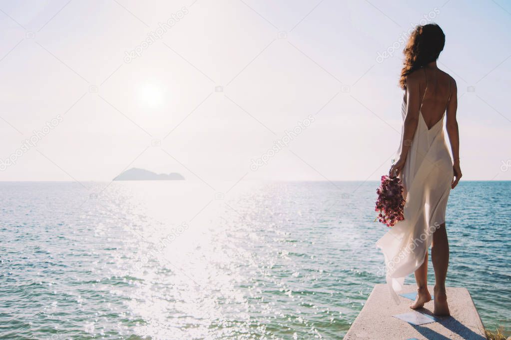 beautiful bride stands on a cliff above the sea