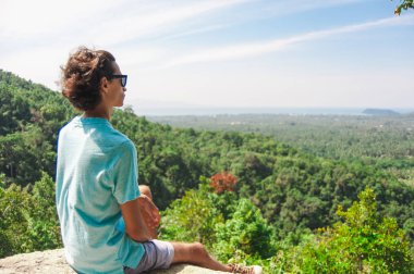 Adam ısmarlayarak izlerken kayaya oturan dağın zirvesinde