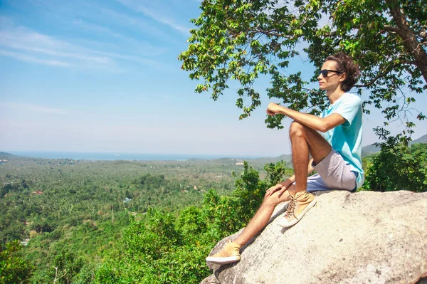 Pria di puncak gunung duduk di batu menonton pemandangan indah — Stok Foto