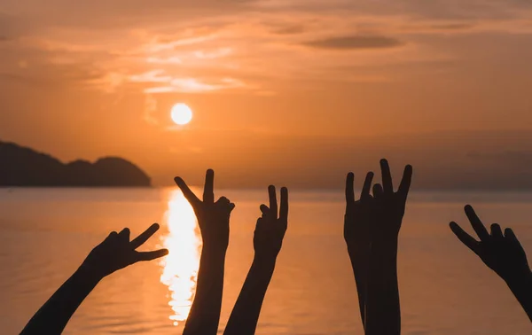 Muitas mãos levantadas contra o céu do pôr do sol — Fotografia de Stock