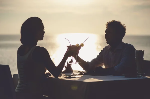 Pareja romántica disfruta de la puesta de sol en el restaurante en la playa bebiendo cócteles —  Fotos de Stock