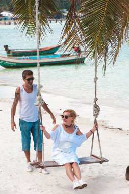 Sahilde tatil, salıncak üzerinde bir kadın Olgun çift