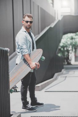 Bir patenci ile bir longboard dışarıda duruyor.