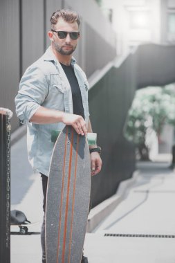 Bir patenci ile bir longboard dışarıda duruyor.