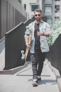 Bir patenci ile bir longboard dışarıda yürüyor.