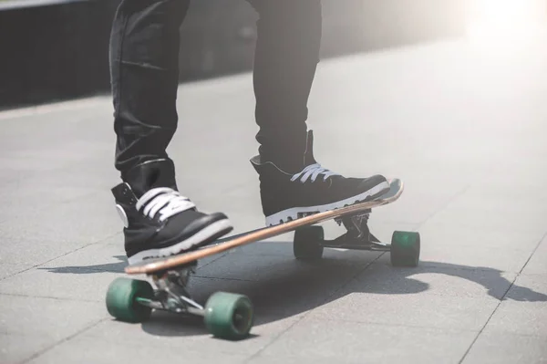 Primer plano de las piernas del patinador en el longboard que monta en la calle al aire libre — Foto de Stock