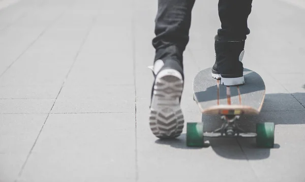 Närbild på skater's ben på den longboard som rider på gatan i utomhus — Stockfoto
