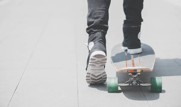Gros plan des jambes du patineur sur le longboard chevauchant la rue en plein air — Photo