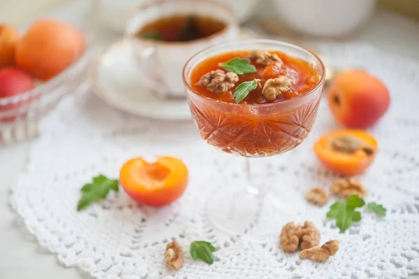 Apricot jam in a glass bowl, fresh apricots in a basket on a white background