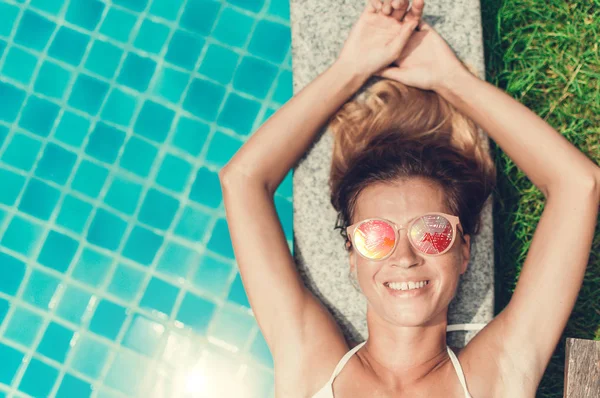 Döşeme ve swimmin havuzda gülümseyen güneş gözlüğü güzel genç kadın modeli