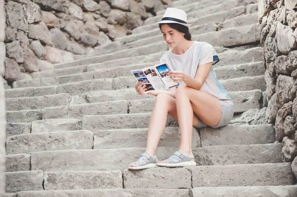 젊은 여자 관광 Rabati 요새에 계단에 앉아서 안내 책자를 읽고 — 스톡 사진