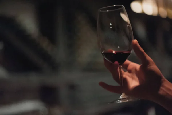 Male sommelier pouring holding wine in long-stemmed wineglasses.