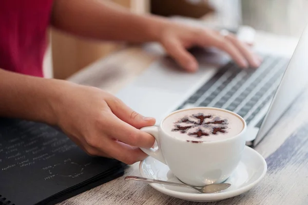 Mladá žena na volné noze psaní v notebooku v kavárně — Stock fotografie