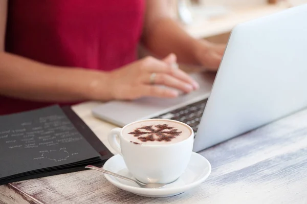 Junge Freiberuflerin tippt in Laptop in Café — Stockfoto