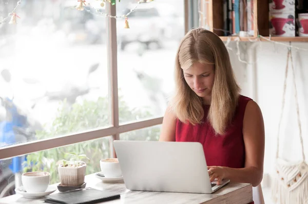 Junge Freiberuflerin tippt in Laptop in Café — Stockfoto