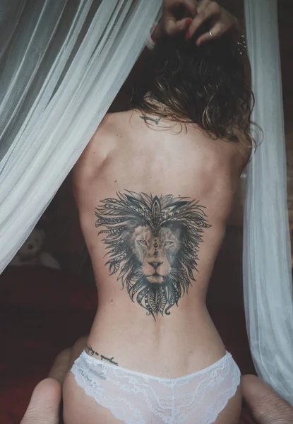 Nu de volta com a tatuagem de um leão de uma jovem mulher sentada em uma cama — Fotografia de Stock