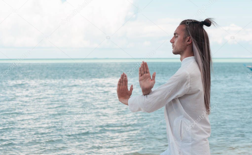 Handsome man is practicing Taijiquan on the beach
