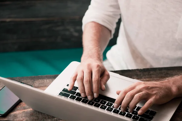 Junger männlicher Freiberufler sitzt im Café und arbeitet im Laptop — Stockfoto