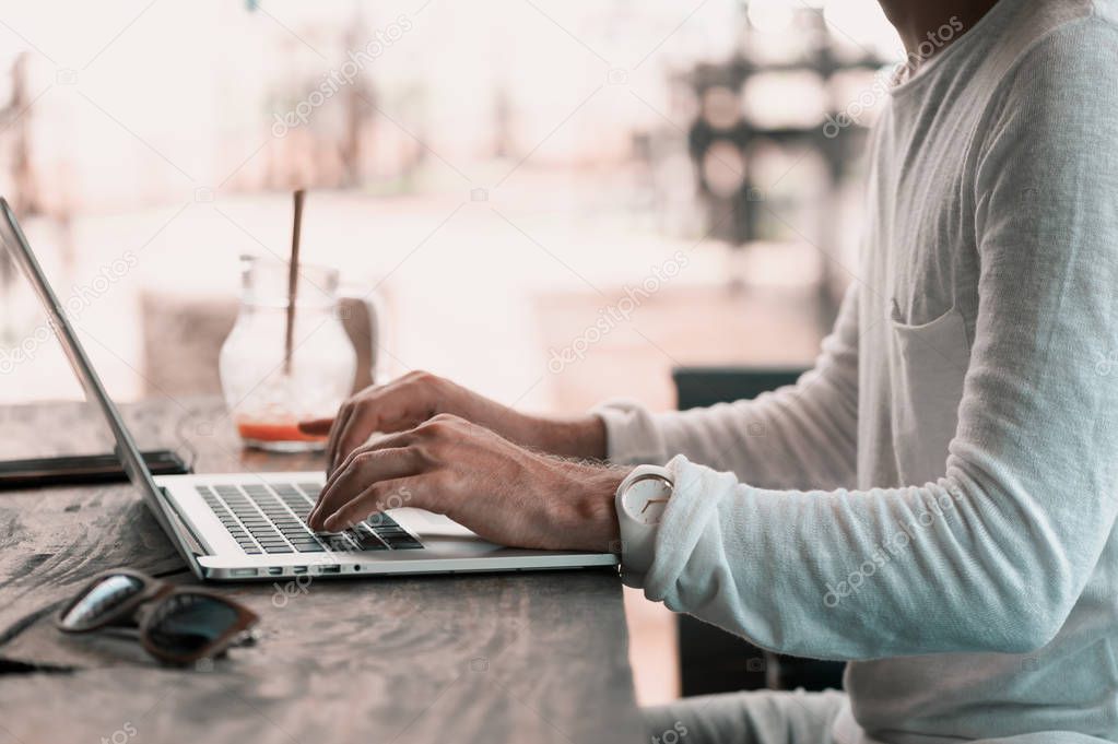 Young male freelancer sitting in cafe working in laptop