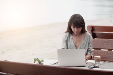 Genç ve güzel bir kız bir kafede oturuyor ve bilgisayarla çalışıyor.