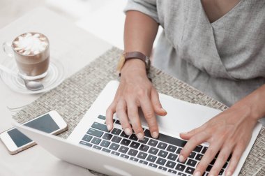 Kafede dizüstü bilgisayar kullanan mutlu kadın. Yakın çekim görünümü