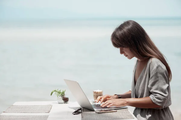 Junges schönes Mädchen sitzt in einem Café und arbeitet am Computer — Stockfoto