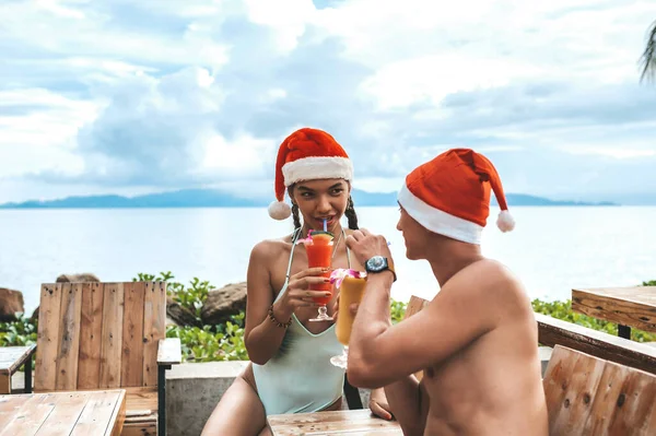 Pareja feliz sentada a la mesa con cócteles y sonriendo —  Fotos de Stock