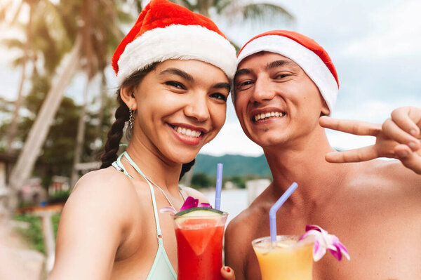 Happy smiling couple in christmas hats doing selfie